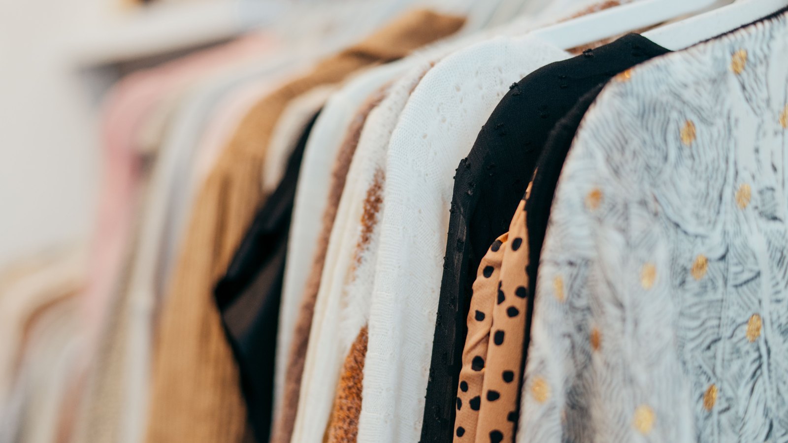 Clothing hangs in a close row on a retail rack.