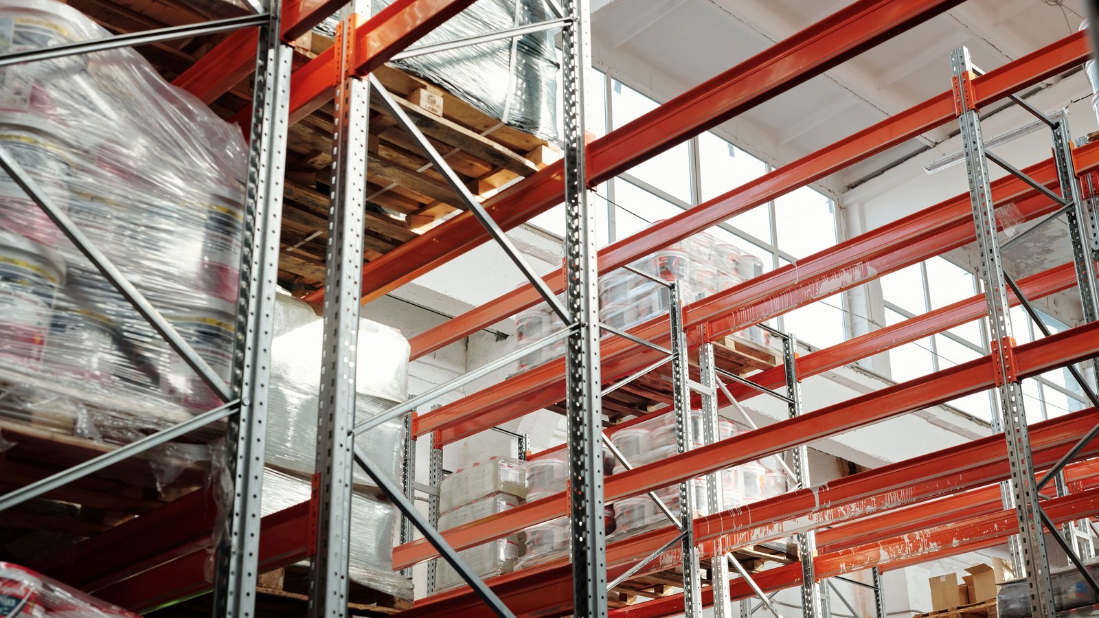 Rows of pallet racks hold wrapped goods in a warehouse.