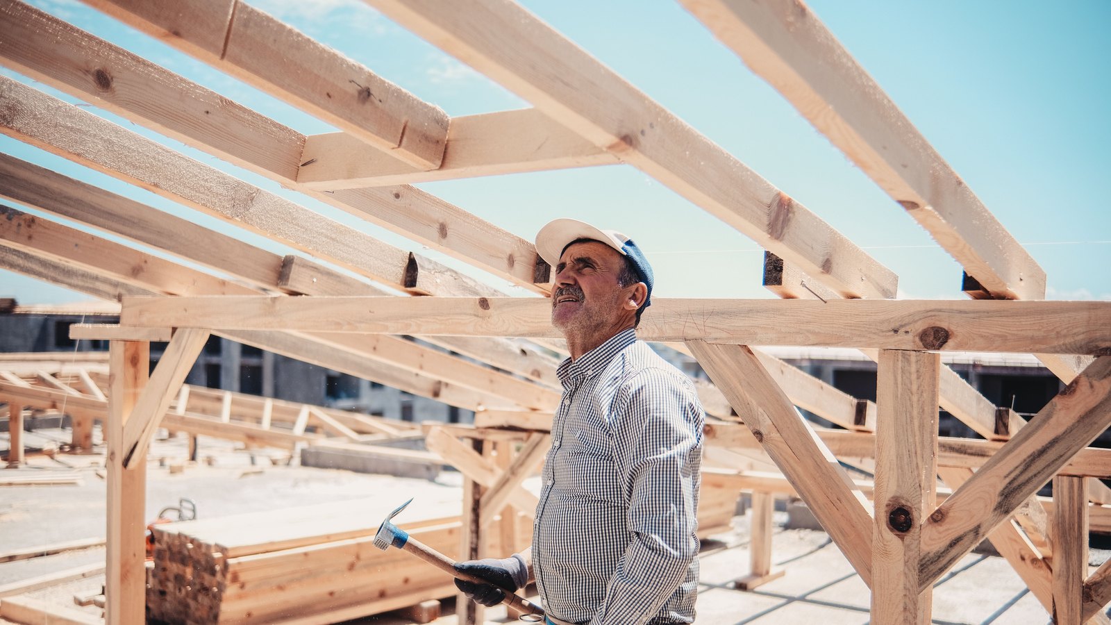 A construction worker inspects the timber framing of a residential roof.