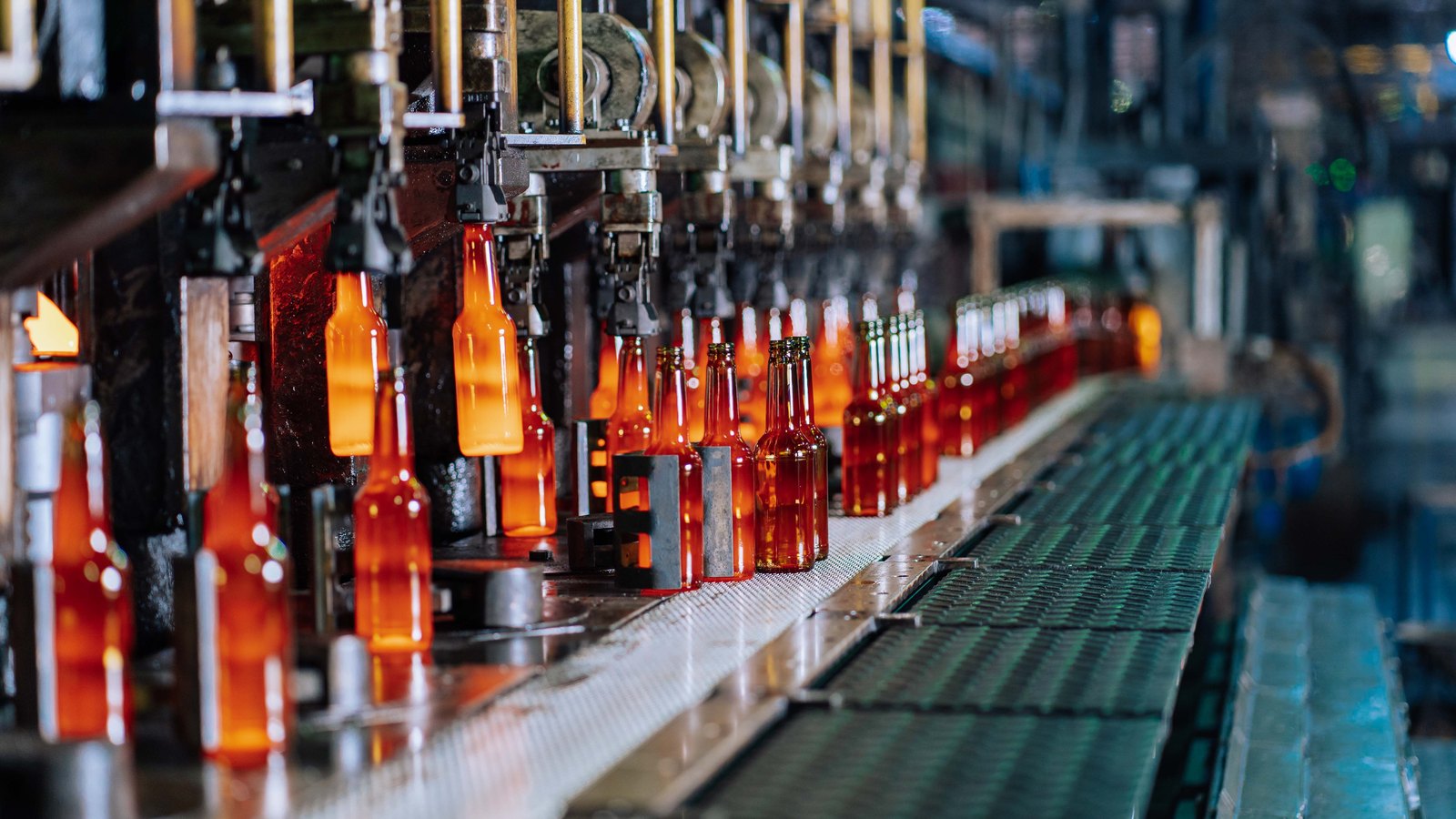 Glowing glass bottles moving through an automated production line.