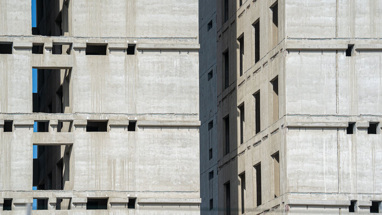 Unfinished concrete building facades with open window bays.