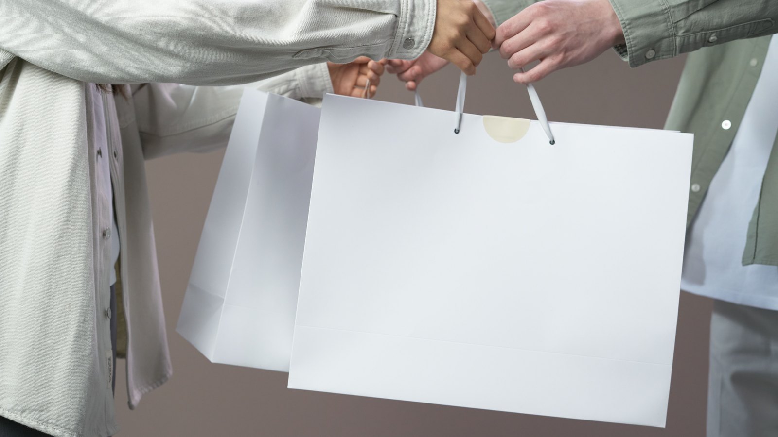 Two people exchange plain white shopping bags.