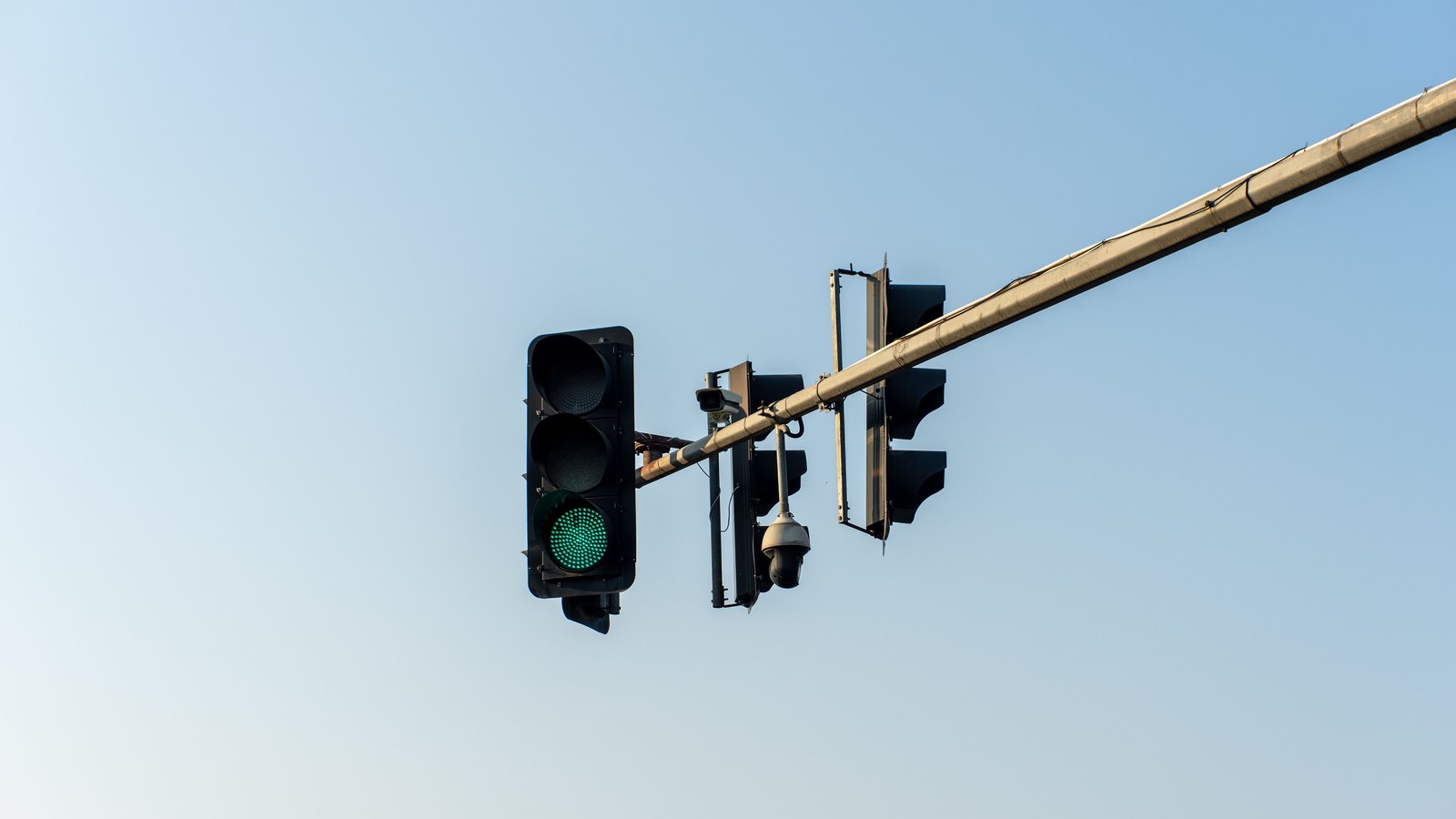 A green traffic signal against a clear sky, not a photograph of this intersection.