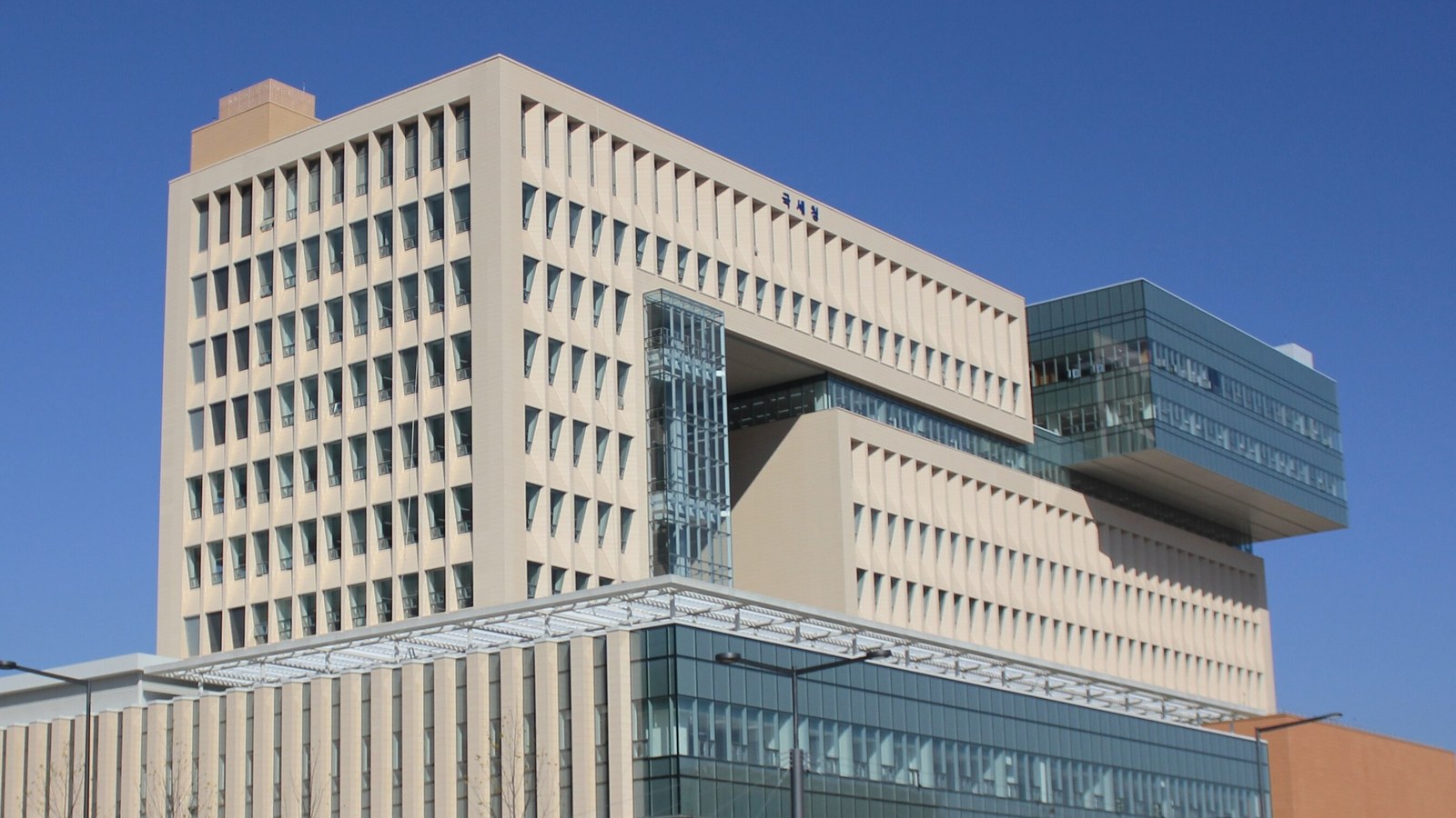 The pale stone and glass headquarters of South Korea's National Tax Service in Sejong under a clear blue sky.