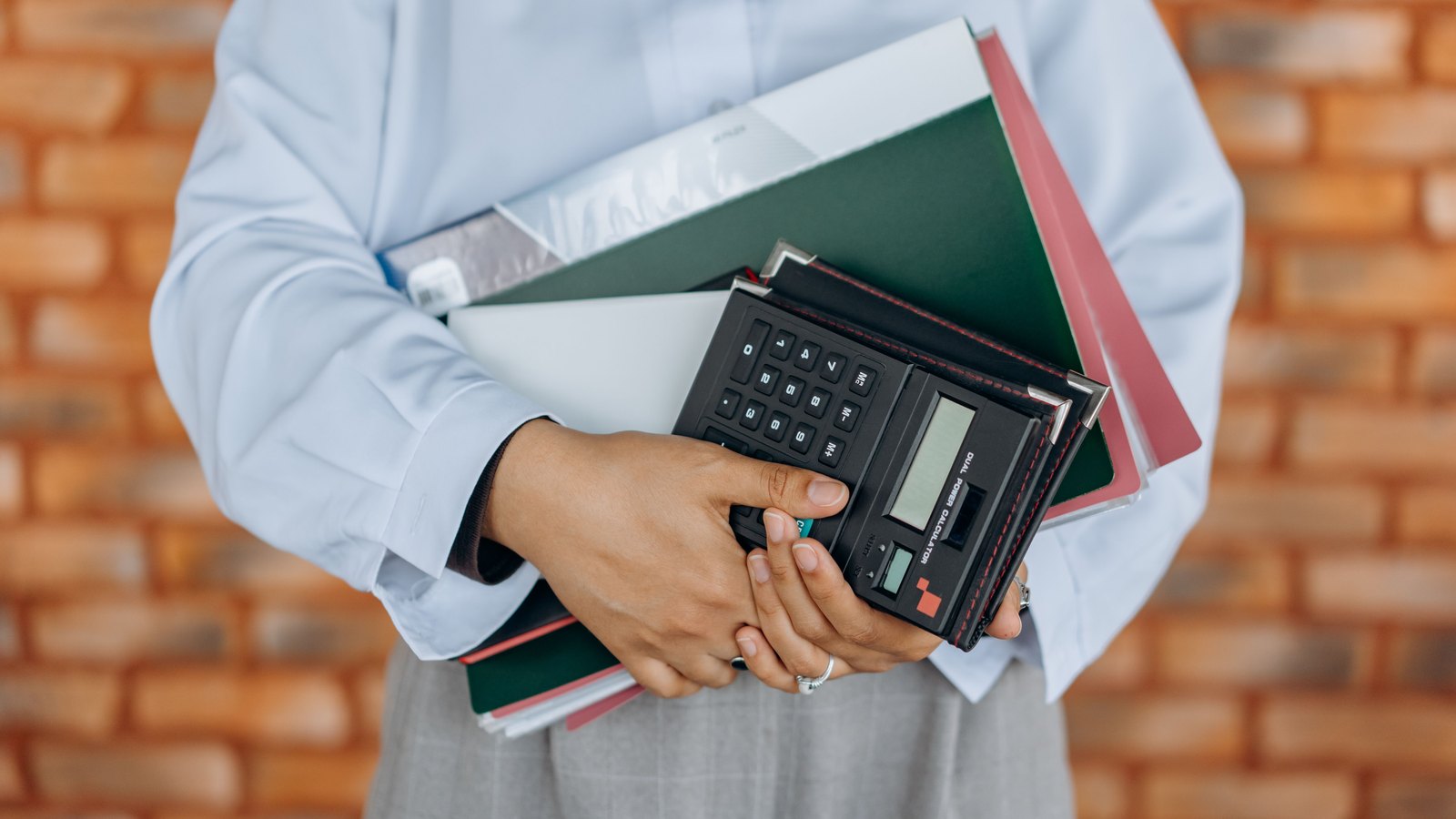 A person holding a calculator and file folders