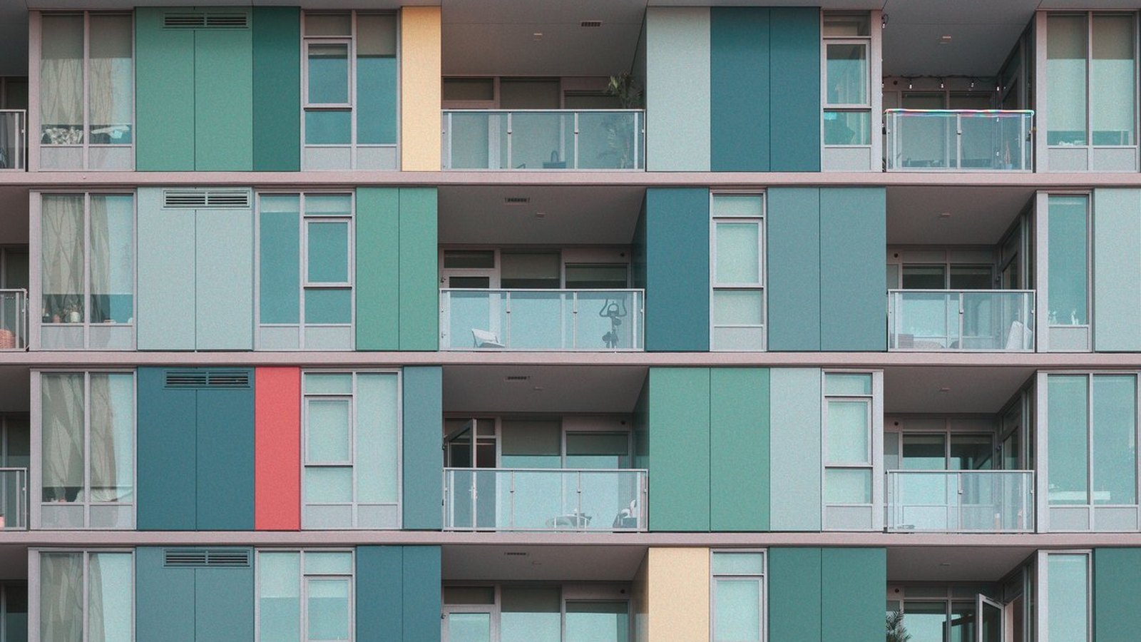 Balconies and coloured facade panels across four floors of a multi-storey residential building.