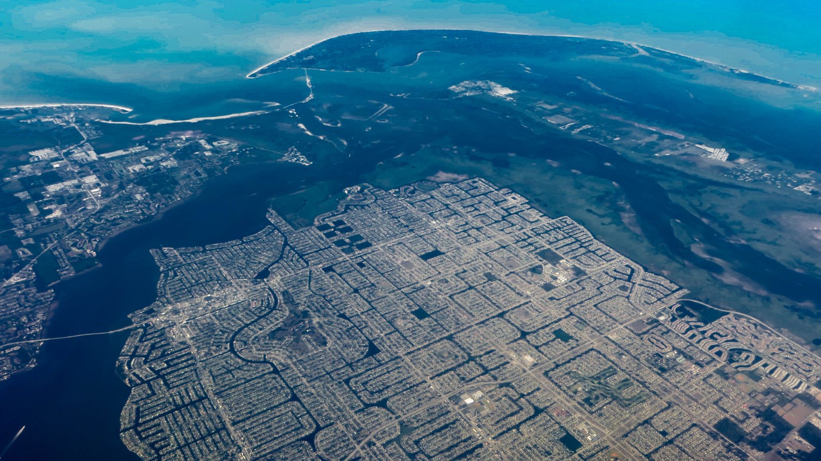 Aerial view of Cape Coral residential streets and canals beside the Caloosahatchee River and Pine Island Sound.
