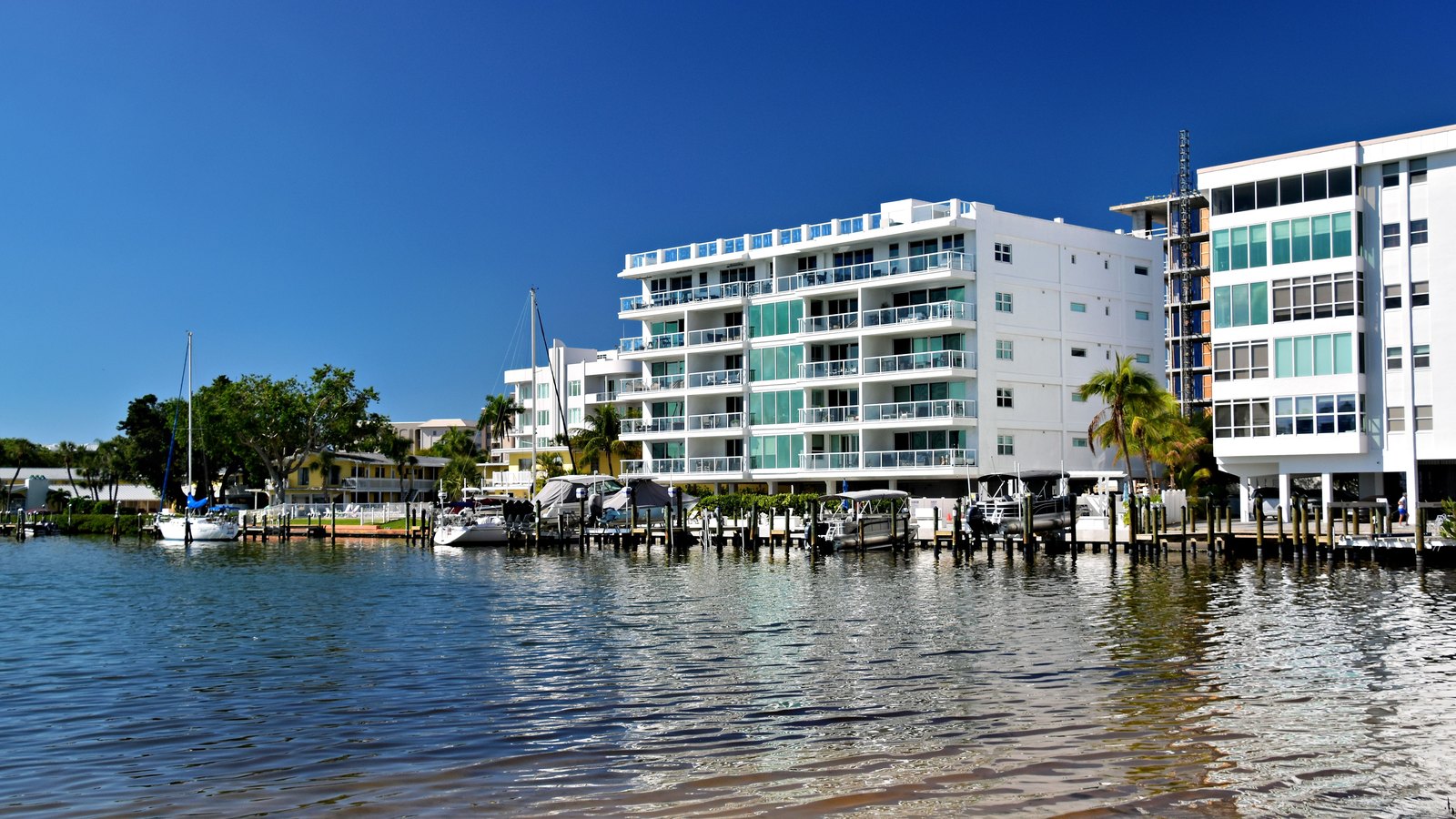 Waterfront condominium buildings beside private docks under a clear blue sky