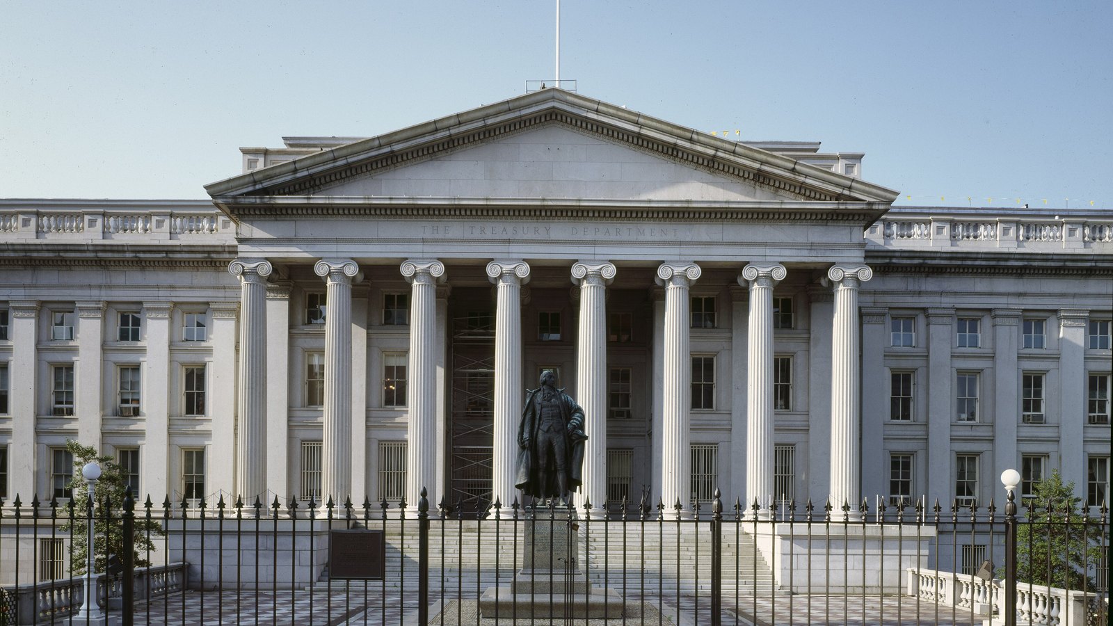 The south front of the United States Treasury Department building in Washington, with its Ionic colonnade and the statue of Albert Gallatin below the pediment.