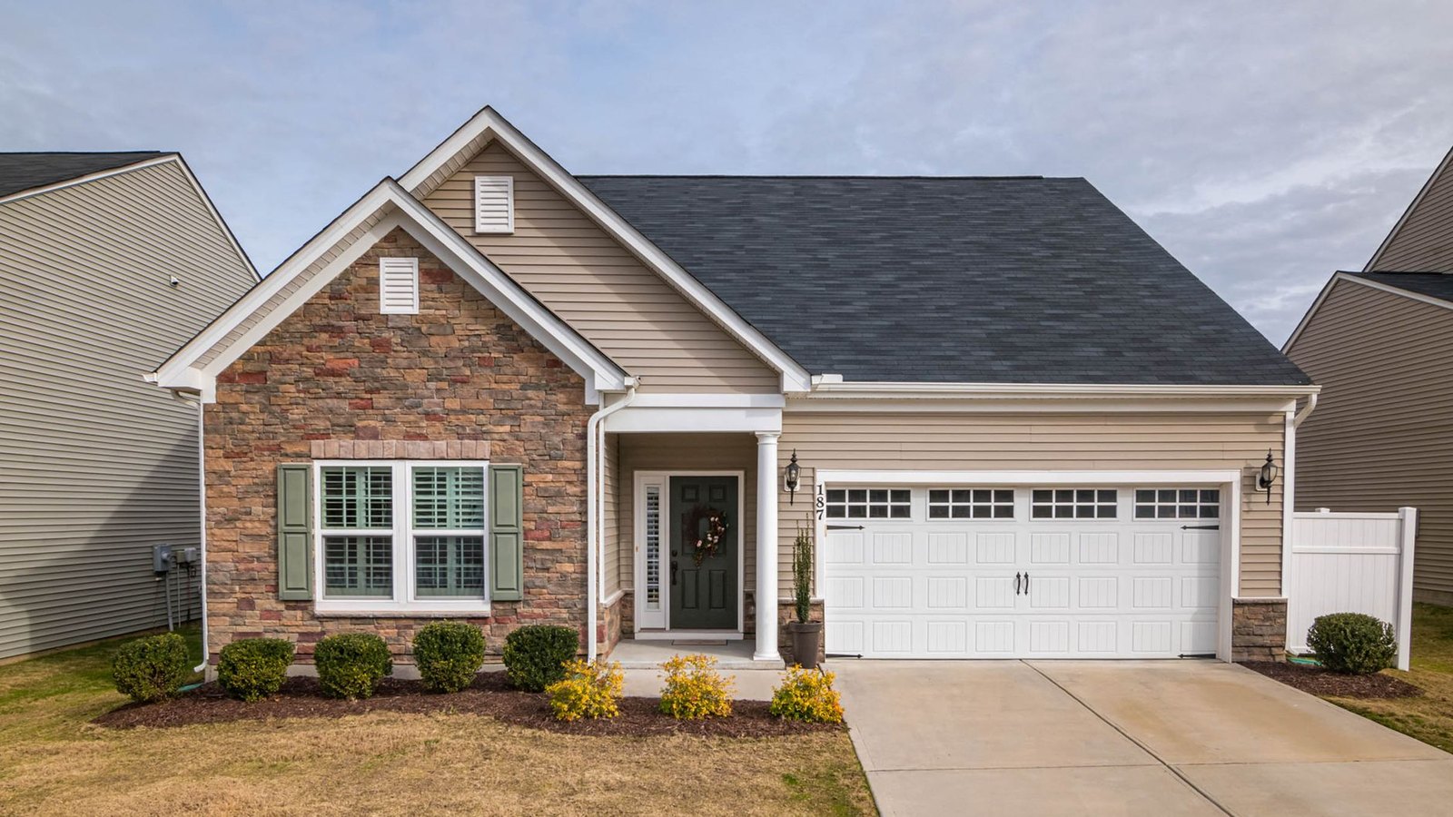 A single-family suburban house with a stone and vinyl facade and a two-car garage.