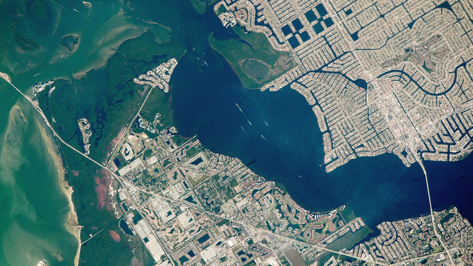 An astronaut photograph of Cape Coral's grid of residential canals, the Caloosahatchee River and the Sanibel Causeway seen from the International Space Station.